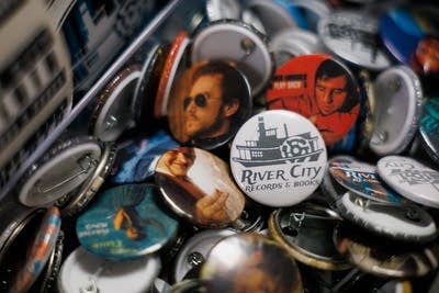 A large quantity of music-themed pin badges on display at a record store
