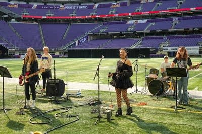A rock band plays on the field at a football stadium.