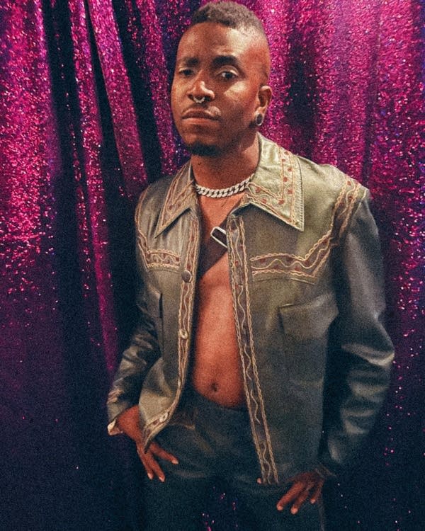 A man poses for a photo in front of a curtain