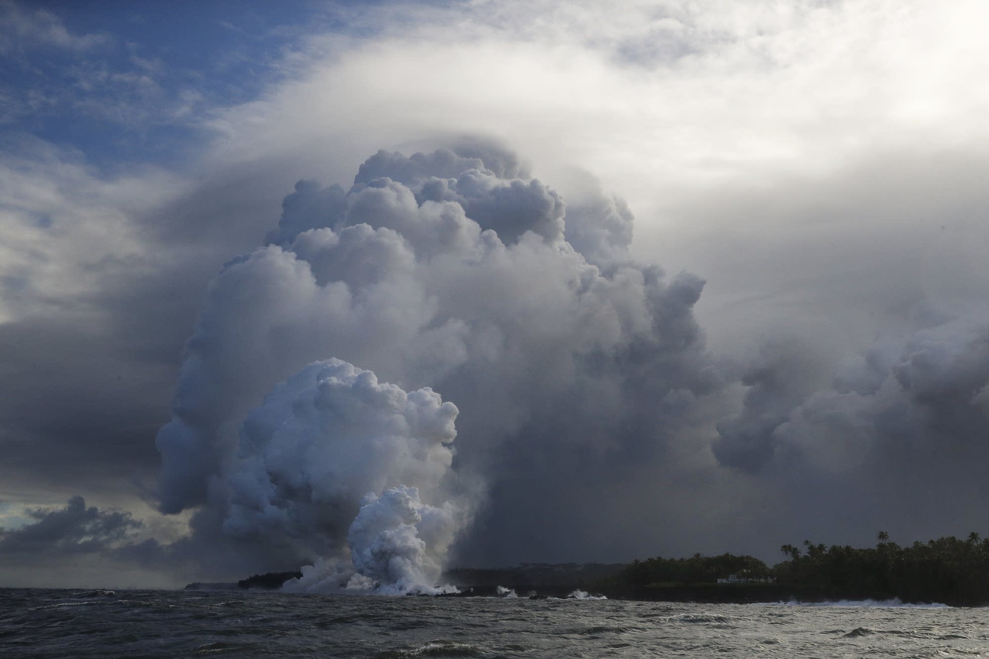 A plume of steam rises as lava enters the ocean near Pahoa, Hawaii.