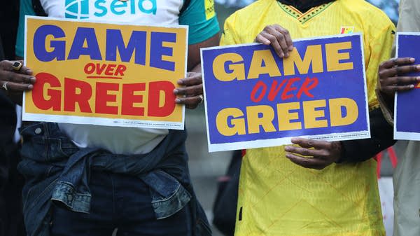 People hold two signs that say "Game over greed."