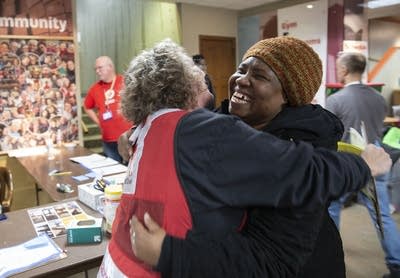 Two women hug in the lobby of a church. 