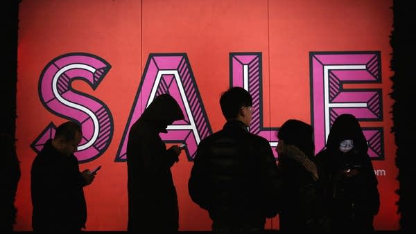 Shoppers line up outside a store sale.