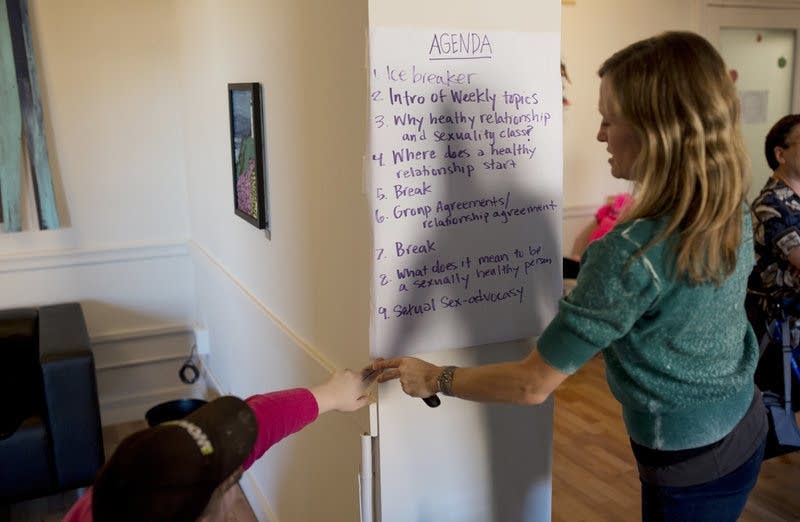 A participant helps Katy Park hang the agenda.