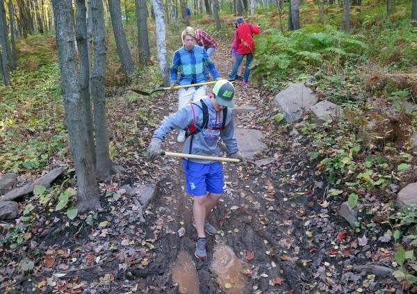 Brennen Larson fixes a muddy spot of a mountain bike trail.