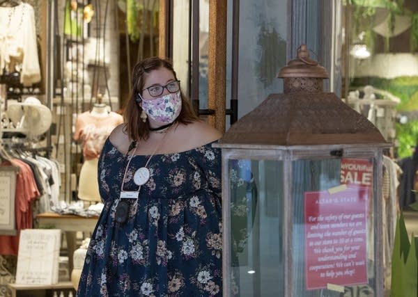 A person wearing a face mask stands at a door.