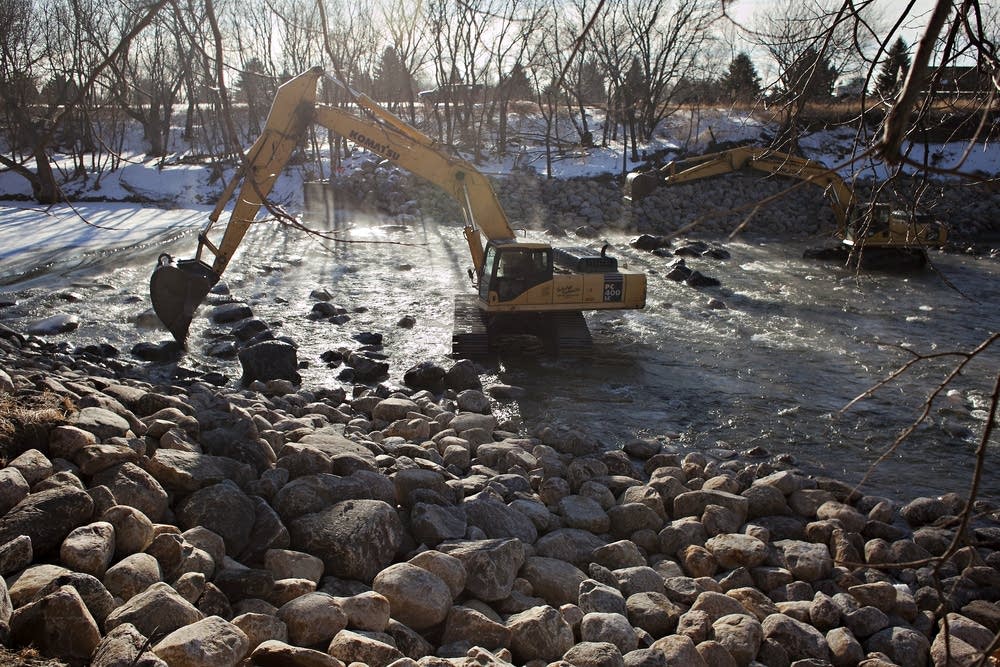 Excavators maneuver boulders