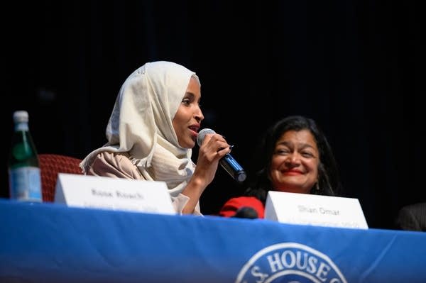 A woman holds a microphone as she speaks at a panel discussion.