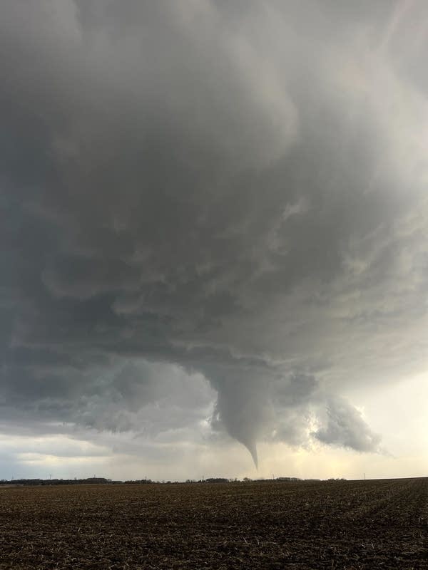 A funnel cloud develops over a field.