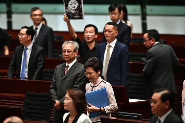A pro-democracy lawmaker holds up a placard in protest as Hong Kong's Chief Executive Carrie Lam prepares to give her annual policy address.