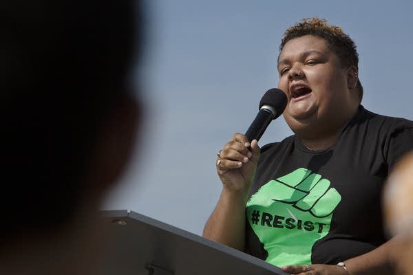 A young adult speaks into a microphone. 