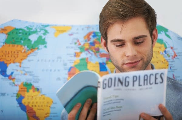 A young man reading a travel magazine (Photo: Getty)