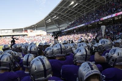 Football players wearing purple jerseys huddle