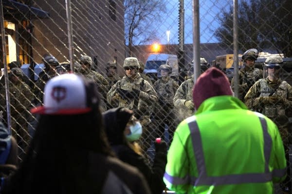 Protesters face off against police behind a fence.