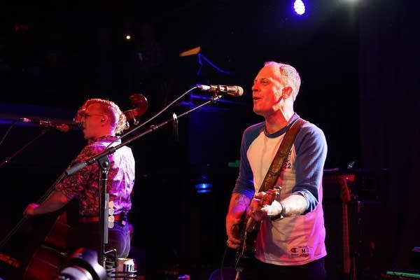 A guitarist and bassist perform on a stage