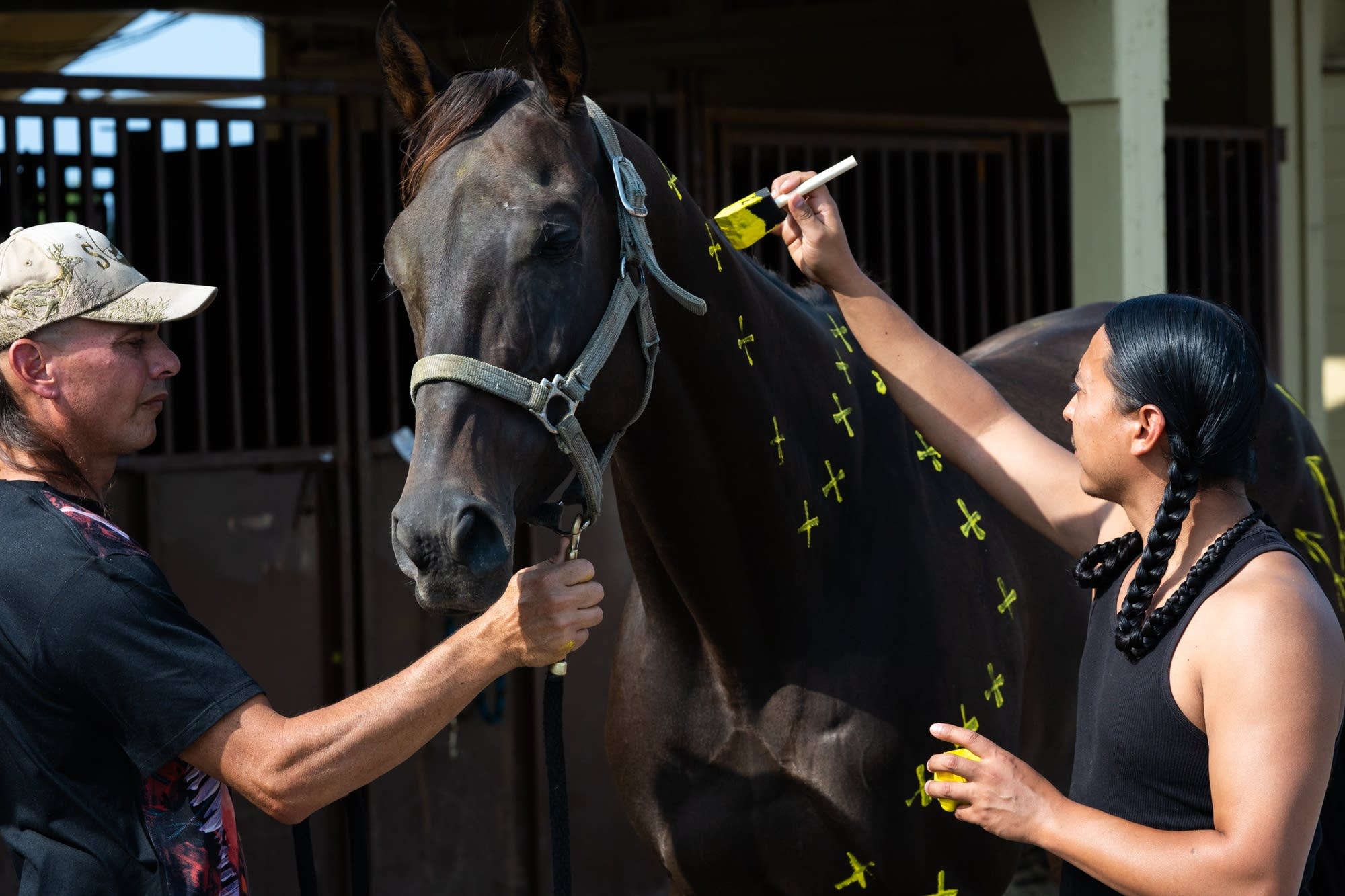 Derek Brown, right, paints one of his father Tim's horses.