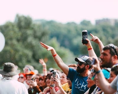 Music fans sing, dance and gesture while a band perform onstage