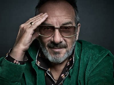 A man in sunglasses holds his right hand to his forehead