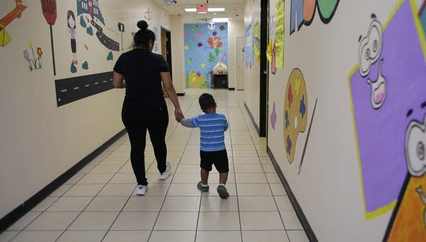 A young migrant boy walks with a Comprehensive Health Services caregiver.