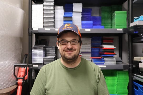 Man in green shirt and a hat poses for photo