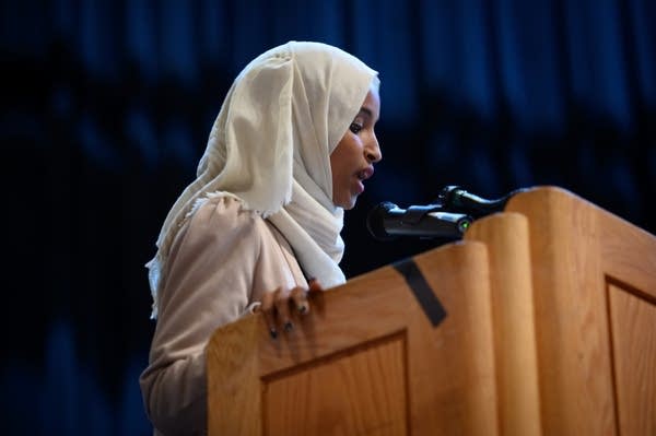 A woman stands at a podium to speak.