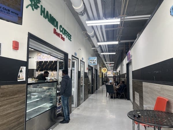 A man orders coffee from a counter in an indoor mall.