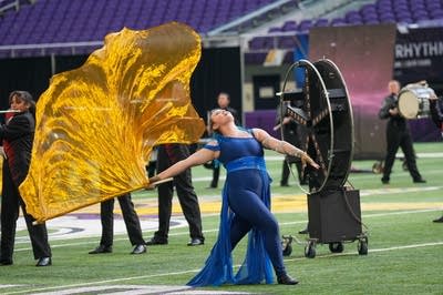 A marching band performs on the field of a football stadium.