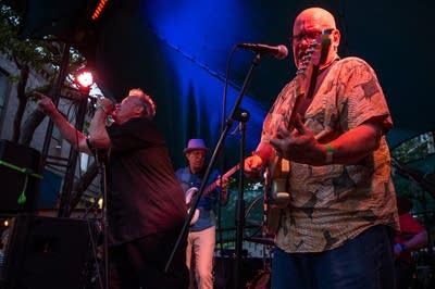 A rock band performing on an outdoor stage