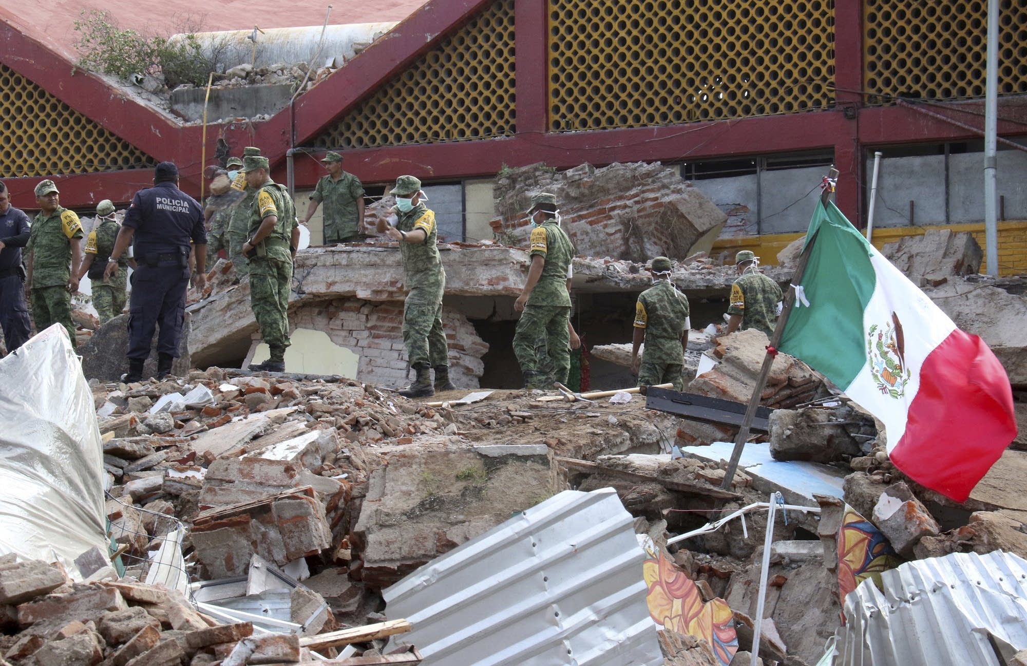 Soldiers remove debris from a partly collapsed municipal building