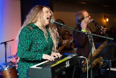 Woman playing keyboard and singing into microphone