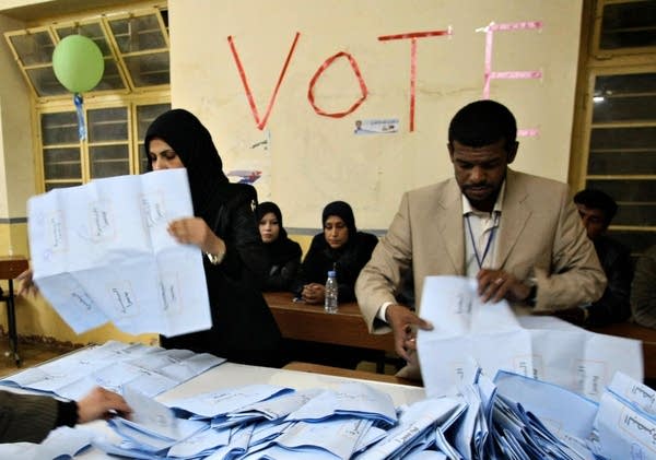 Iraqi electoral workers empty ballot box