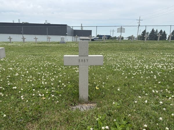 A stone cross in a cemetery with only the word 'baby'