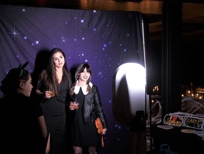 Two people in costume stand in front of a starry backdrop