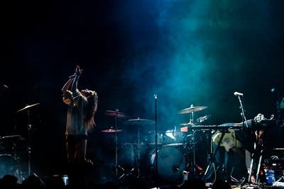 A musician sings and dances onstage in a large music venue