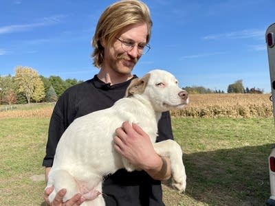 A man holds a dog up in his arms.