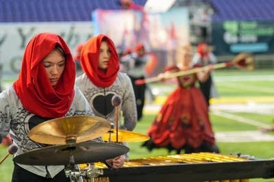 A marching band performs on the field of a football stadium.