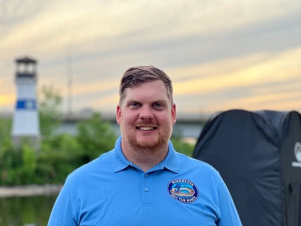 man smiles in front of lighthouse
