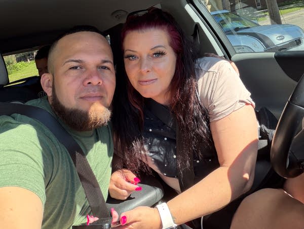 A man and woman pose for a selfie in a car