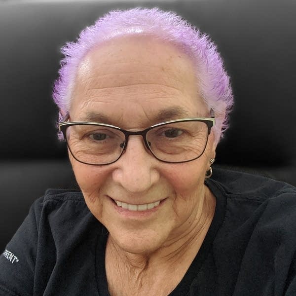 A woman with bright pink short hair and glasses.