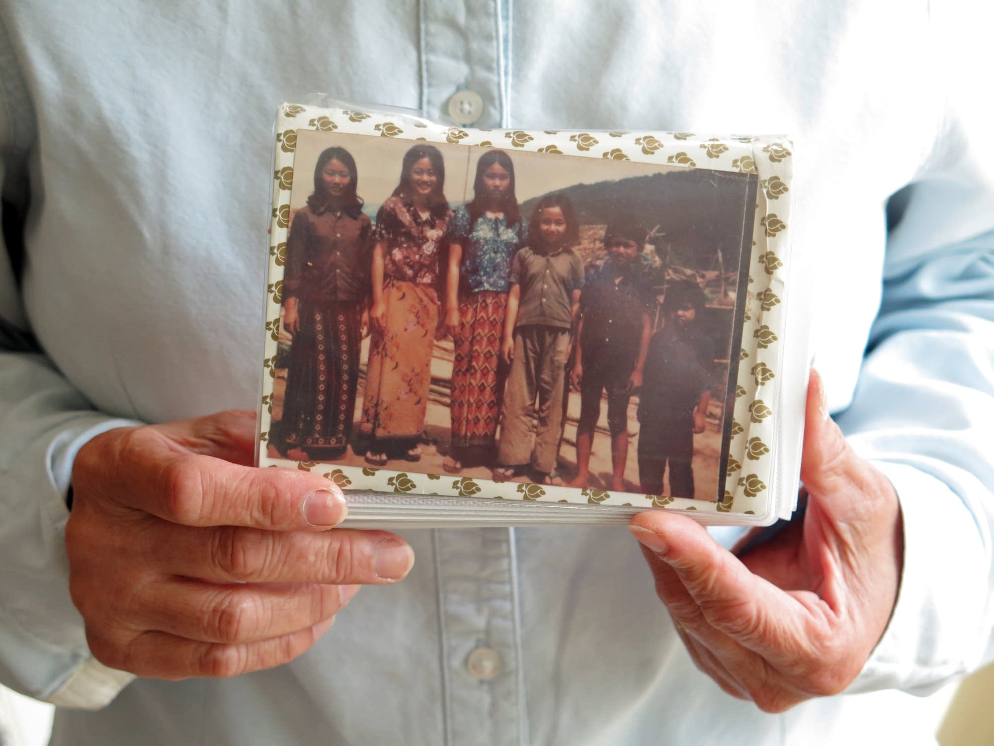 Sova Niev holds a photo of her and her siblings in a refugee camp.