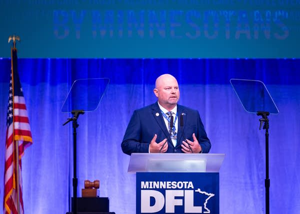 A man speaks at a podium on stage.
