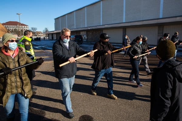 A group of plain clothes police officers march with batons.