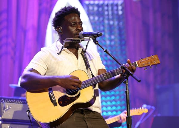 A musician sings and plays guitar onstage