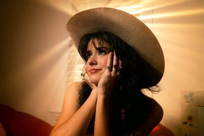 A woman in a cowboy hat holds her face in her hands