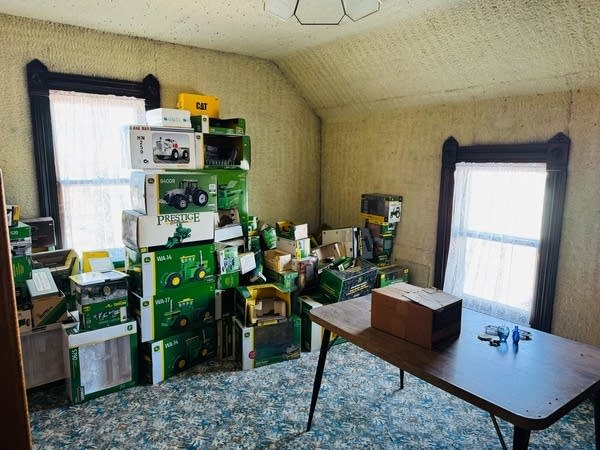 Boxes of John Deere items sit on the far wall of a sparse room.