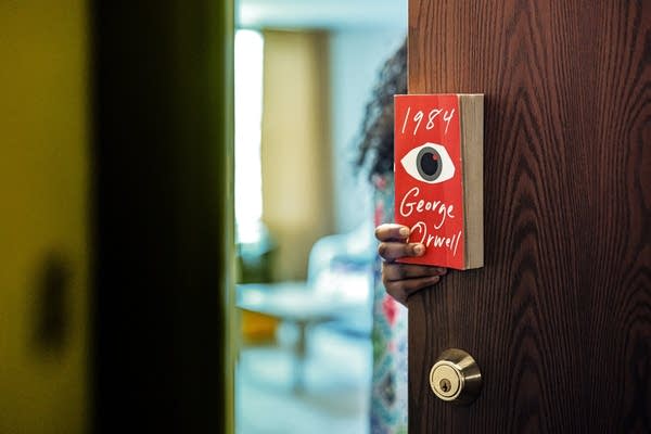 A person holds a copy of George Orwell’s “1984,