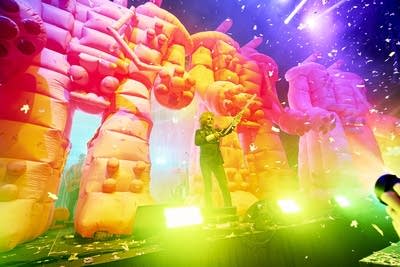 A musician standing before an army of inflatable robots assembles some PVC piping