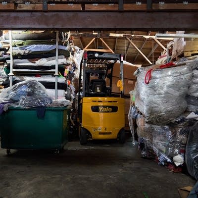 A forklift is used to remove and move bails of textiles