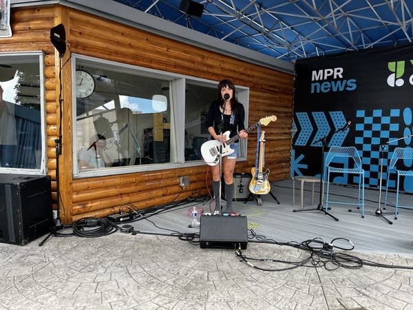 A woman performs with a guitar.