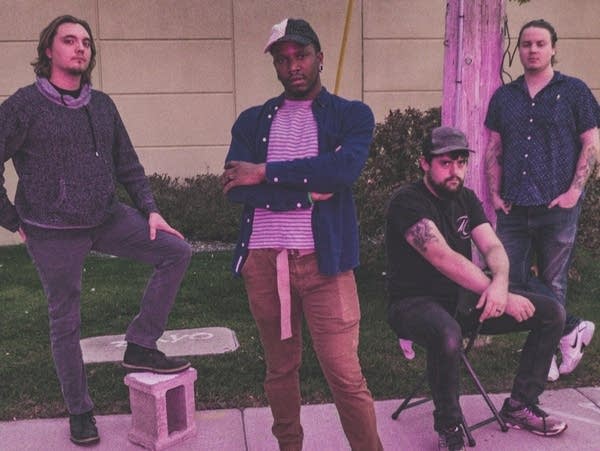 Four men stand together on a sidewalk